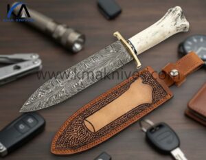 KMA HAND FORGED FEATHER PATTERN DAMASCUS STEEL COMBAT DAGGER KNIFE WITH BRASS CLIP AND FILE-WORKED BRASS SPACER WITH BONE HANDLE AND LEATHER SHEATH.